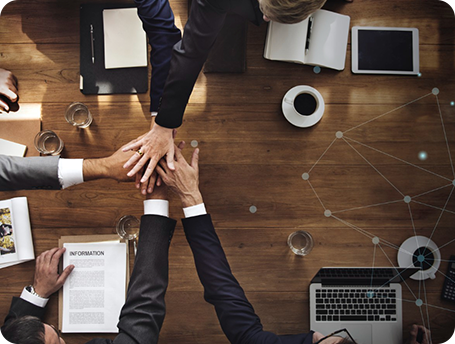 Team members joining hands over a desk during a planning meeting